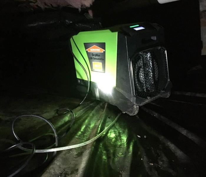green dehumidifier set inside of a flooded crawl space